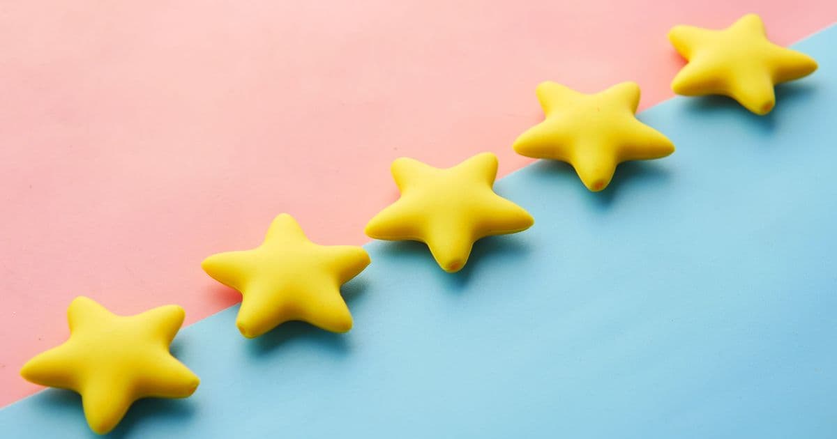 Yellow stars on pink and blue pastel background for rating or review concept.